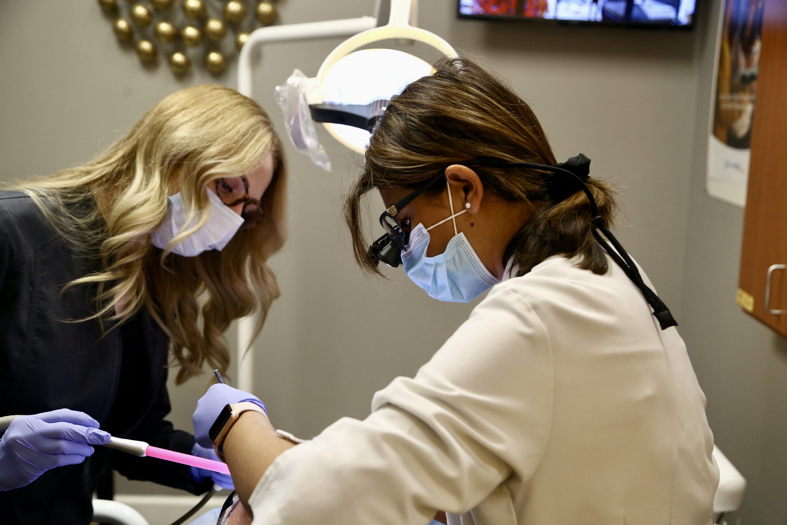 Two Natural Smiles Dentistry clinicians performing a precision procedure with loupes and operatory light — implant dentist in Chandler AZ